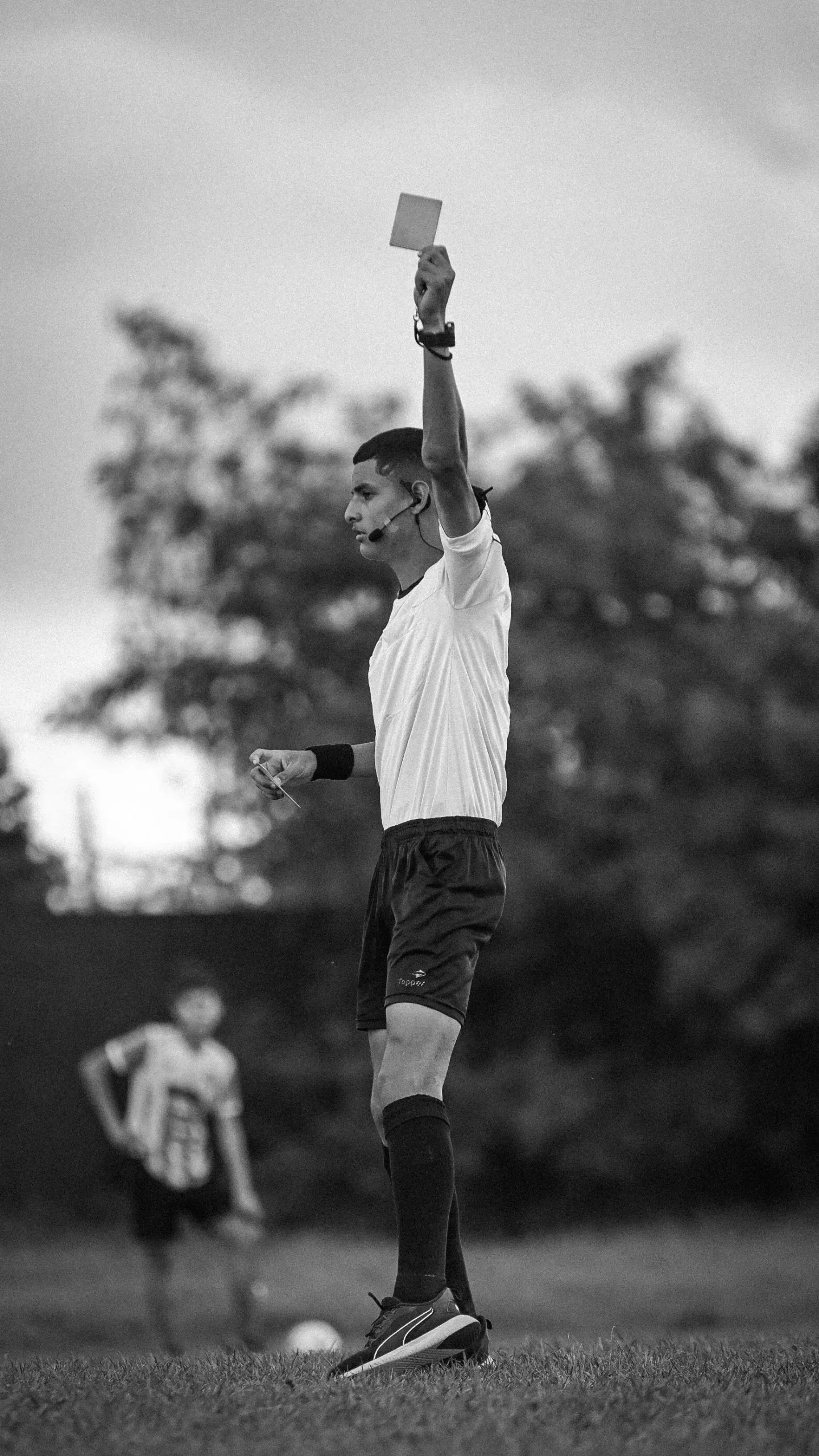 Arbitro mostra il cartellino giallo durante una partita di calcio, foto in bianco e nero